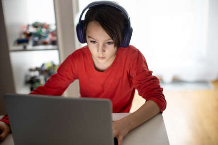 Child, preteen boy, learning  for school on computer at home, after school homeworks
