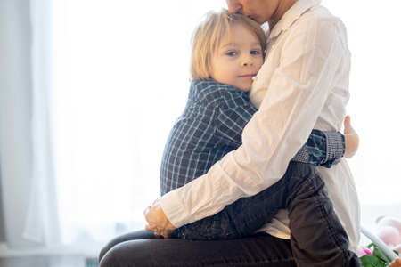 Portrait of mother and child, hugging on a back lit white background, enjoying family time togetherの写真素材