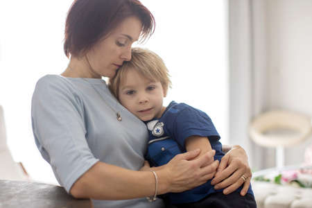 Portrait of mother and child, hugging on a back lit white background, enjoying family time together
