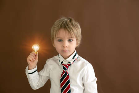 Cute toddler child, boy with smart casual clothing on isolated background, holding light bulbs, studio shotの写真素材