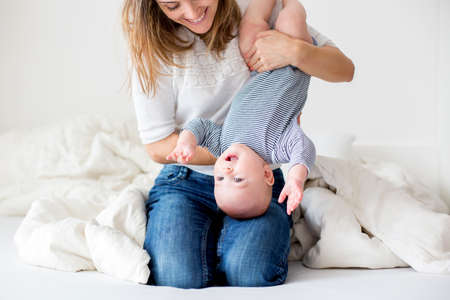 Mother and her little baby boy, playing together in bedrroom, happy family conceptの写真素材