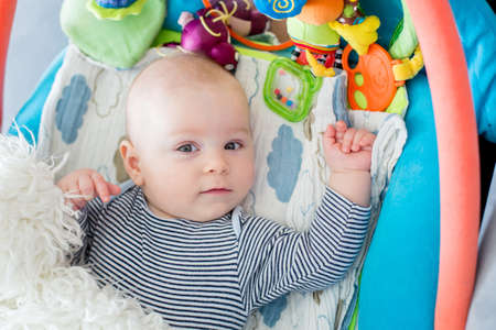 Portrait of a baby boy, lying down on a playmat with soft toys around, portrait from aboveの写真素材