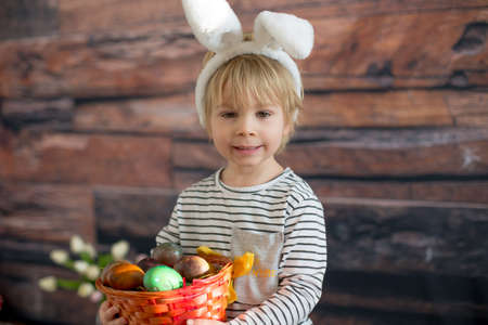 Sweet toddler child, cute boy playing with colorful easter eggs, studio shot