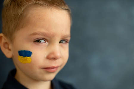 Young blond child, holding sign in support to peace, no war wanted, kid wishing peaceful life. Picture in connection with the continuing war in Ukraineの写真素材