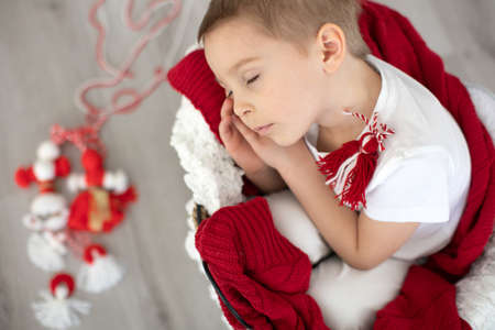 Cute child, blond boy, playing with white and red bracelet, bulgarian martenitsaの写真素材