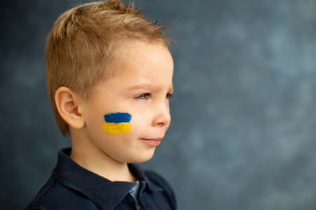 Young blond child, holding sign in support to peace, no war wanted, kid wishing peaceful life. Picture in connection with the continuing war in Ukraineの写真素材