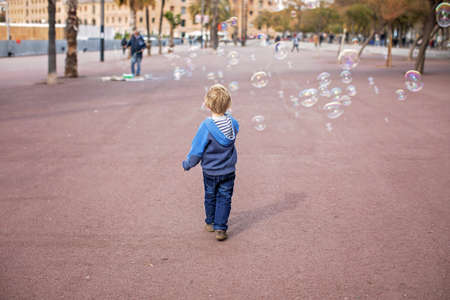 Cute little child tourists, playing with soap bubbles, admiring Barcelona city, family travel with kids in Spainの写真素材
