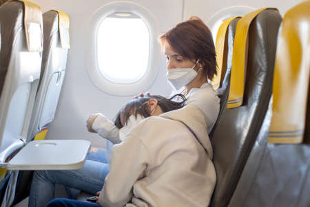 Mother and child, boy and mom, sitting in airplane, having nausea, unease and discomfort from the turbulenceの写真素材
