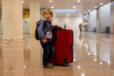 Cute  baby boy waiting boarding to flight in airport transit hall near departure gate. Active family lifestyle travel by air with child on vacationの写真素材