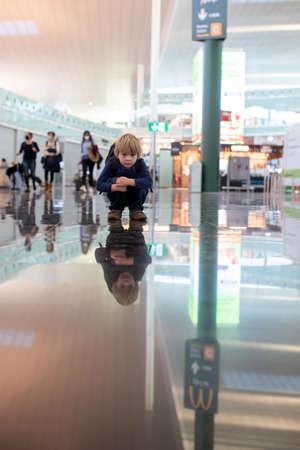 Cute  baby boy waiting boarding to flight in airport transit hall near departure gate. Active family...