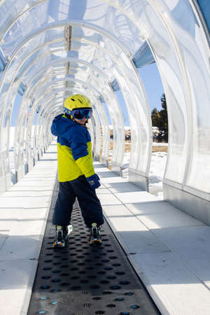Cute toddler child in colorful ski wear, skiing in Italy on a sunny day, kids and adults skiing together. Family vacationの写真素材