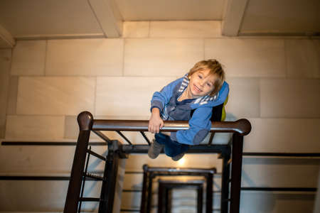 Spiral staircase in a bluildin, child, standing on the lower floor, looking at camera, view from aboveの写真素材