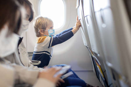 Mother and child, boy and mom, sitting in airplane, child playing on tablet, family tripの写真素材