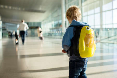 Cute  baby boy waiting boarding to flight in airport transit hall near departure gate. Active family lifestyle travel by air with child on vacationの写真素材