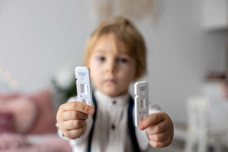 Child, holding two home made covid 19 SWAB antigen test, home allowed tests, showing positive and...