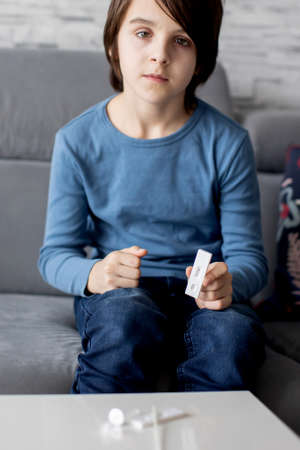 Child, holding home made covid 19 SWAB antigen test, home allowed tests, showing positive/negative...