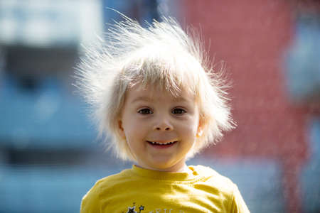 Cute little boy with static electric hair, having his funny portrait taken outdoors on a trampolineの写真素材