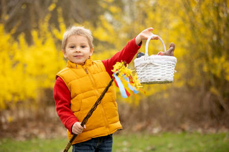 Cute preschool child, boy, holding handmade braided whip made from pussy willow, traditional symbol of Czech Easter used for whipping girls and women to receive eggs and sweetsの写真素材