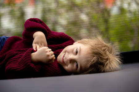 Cute little boy with static electric hair, having his funny portrait taken outdoors on a trampolineの写真素材