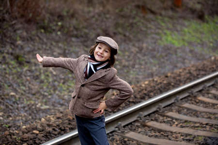 Adorable boy on a railway station, waiting for the train, running and playingの写真素材