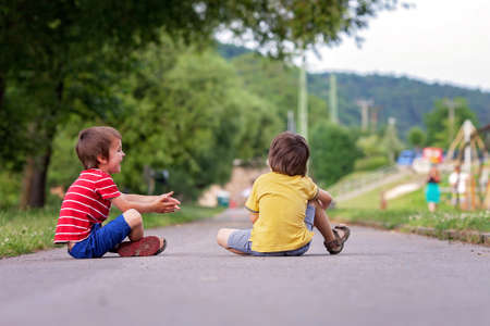 Two cute little kids, playing football together, summertime. Children playing soccer outdoorの写真素材