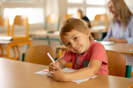 Preschool child, sitting on a desk at school, having lesson, learning new thingsの写真素材