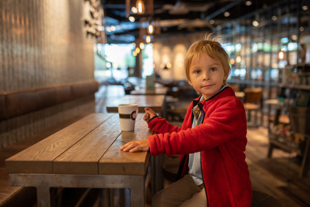 Child, visiting little town in south Norway, Arendal, on a rainy summer day, sitting in a coffee shopの写真素材