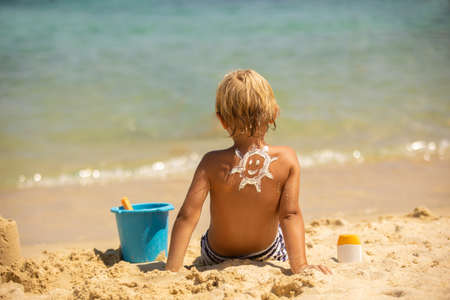 Happy child, blond boy on the beach with applied sun screen,  enjoying summer, playing. Halkidiki, Greeceの写真素材