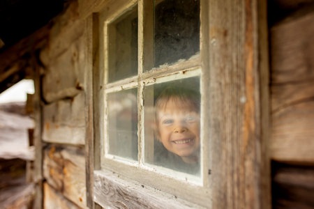 Amazing little wooden small house next to a waterfall on the dock of Hellesylt, child playing in the house, looking out of the windowの写真素材