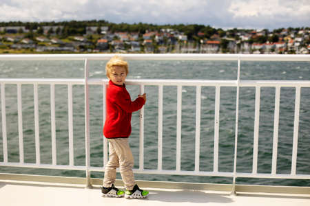 Children, experience ride with ferry on a fjord, strong wind on the deck of the ferry on a sunny dayの写真素材
