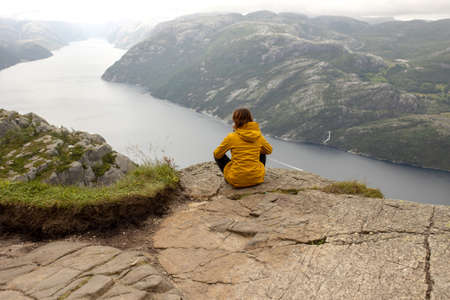 Family, enjoying the hike to Preikestolen, the Pulpit Rock in Lysebotn, Norway on a rainy day, toddler climbing with his pet dog the one of the most scenic fjords in Norwayの写真素材