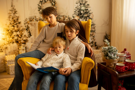 Children, boy brothers, sitting on a yellow armchair in a decorated room for Christmas, cozy placeの写真素材