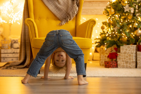 Cute child, boy, sitting on a yellow armchair in a decorated room for Christmas, cozy placeの写真素材