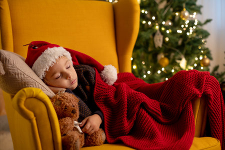 Cute child, boy, sleeping in yellow armchair in a decorated room for Christmas, cozy placeの写真素材