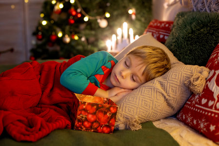 Cute preschool child, blond boy with pet dog, opening presents at home, decorated Christmas room  at homeの写真素材