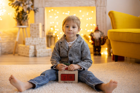 Cute preschool child, blond boy with pet dog, playing in decorated Christmas room at homeの写真素材