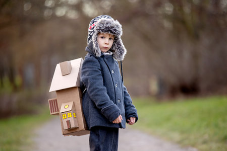 Little child, blond boy with pet dog, carying home on his back, kid, having paper house, emotional shotの写真素材