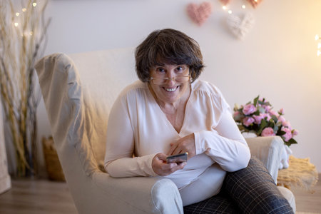 Elderly woman, posing at home, sitting on sofa or bedの写真素材