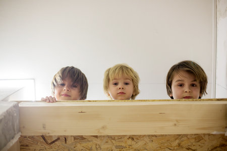 Three children, boy brothers, lying down in narrow gap over the doors at homeの写真素材
