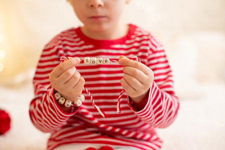 Cute preschool boy, playing with white and red bracelets. Martenitsa, white and red strains of yarn, Bulgarian folklore tradition, welcoming spring in March, adornment symbol, wish for good heathの写真素材