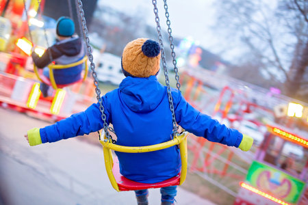 Child, cute boy riding chain swing carousel on sunset, motion blur, colorful backgroundの写真素材