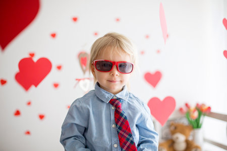 Cute blonde toddler boy, holding heart toy and playing with hearts for Valentine. be my valentine kidの写真素材