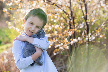 Preschool child, cute boy, playing with little rabbit outdoors, kid and bunny in garden