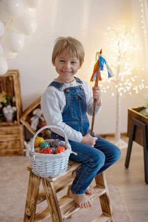 Sweet preschool boy in studio, playing with, egg for Easter and eating chocolate, child on Easter...