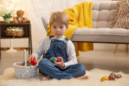 Sweet preschool boy in studio, playing with, egg for Easter and eating chocolate, child on Easter...