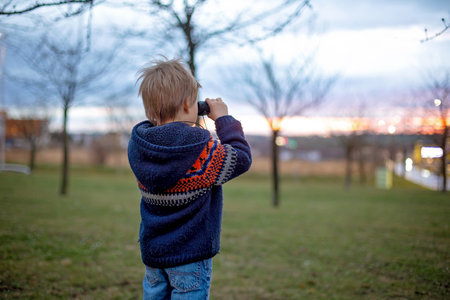Child, watching amazing sunset with binoculars springtimeの写真素材