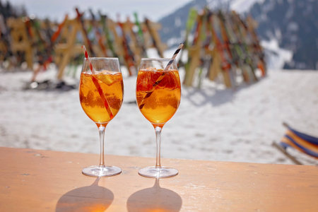 Happy family, enjoying ski holiday with children, sunny beautiful weather outdoors, people drinking aperol spritz on a sunny dayの写真素材