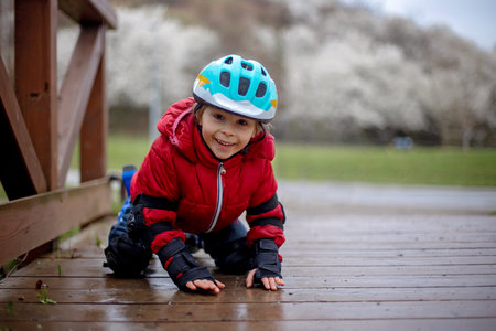 Little child, preschool boy in protective equipment and rollers blades, riding on walkway in parkの写真素材