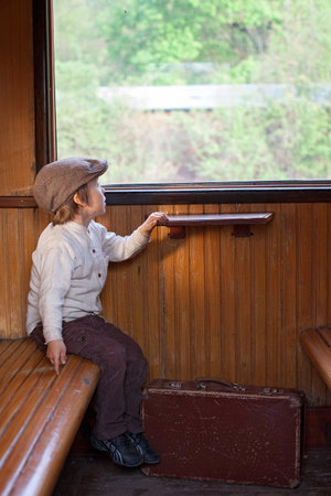 Two boys, dressed in vintage clothing and hat, with suitcase, on a railway stationの写真素材