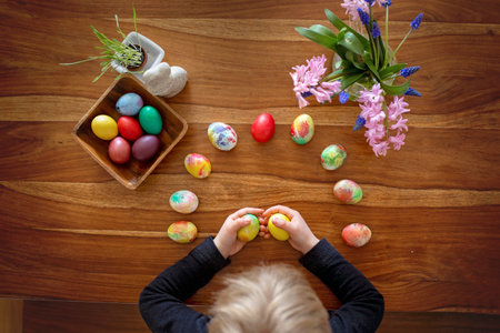 Little blond toddler boy child coloring easter eggs at home, Czech Republic tradition with twigs and eggsの素材 [FY310206495721]